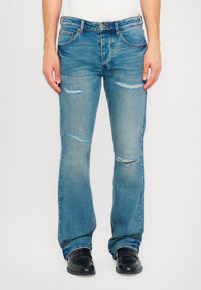 Jean en denim bleu évasé avec une finition délavée, des genoux effilochés et un léger effet de frottement. Comprend un design classique à cinq poches et des passants de ceinture.