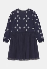 Abito lungo a maniche lunghe blu navy con motivi di stelle argentate nella parte superiore e una gonna a strati in tulle.