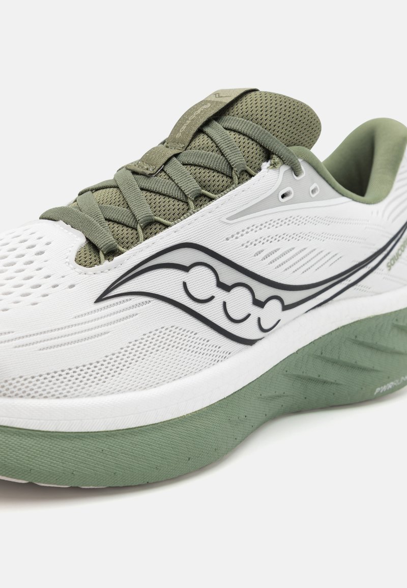 Zapatilla deportiva blanca con acentos verdes, parte superior de malla, superficie texturizada y detalle de logotipo prominente. Cuenta con una suela acolchada para mayor soporte.