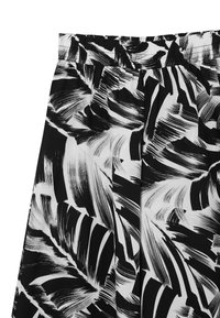 Blusa bianca e nera con tessuto testurizzato, caratterizzata da un audace motivo astratto a foglia e una vita elasticizzata per una maggiore flessibilità.