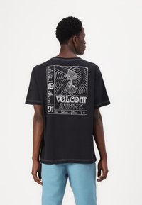 Black cotton t-shirt featuring a graphic design on the back with white text and illustrations, short sleeves, and contrasting stitching detail.