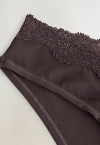 Tumepruuni naiste aluspesu, millel on lai lilleline pitsvöö ja sile kangas kehaosas, heledal taustal.