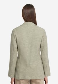 Ljusgrön texturerad kavaj med skräddarsydd passform, slagkrage och långa ärmar. Tyget har ett subtilt vävt mönster.