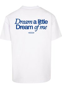 Hvid bomulds t-shirt med blå tekst på ryggen: "Dream a little Dream of me" med "UPSCAL" logo nedenunder. Korte ærmer, rund hals.