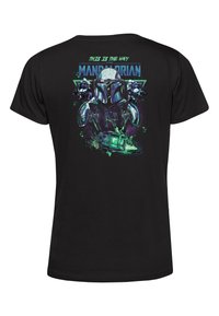 Svart t-shirt med ett grafiskt design av en karaktärshjälm med texten "DETTA ÄR VÄGEN" i grönt och blått, med sci-fi-element.