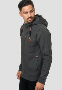 Sudadera gris hecha de una tela suave, con cremallera frontal, cordones con acentos de cuero y bolsillos laterales con detalles triangulares de cuero.