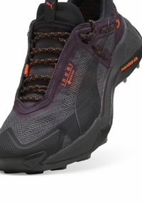 Tumehallid Gore-Tex sneakerid oranžide aktsentidega, tekstureeritud võrkkangast pealisosa, polsterdatud kaelus ja tugev kummipohjaga, mis on loodud haarduvuse tagamiseks.