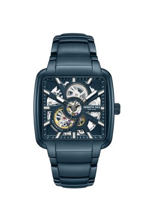 Orologio automatico quadrato con cassa e bracciale in metallo blu scuro. Il quadrante presenta un design a scheletro con ingranaggi visibili e dettagli argentati.
