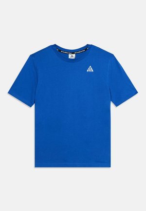 Blå T-shirt med korte ærmer og rund halsudskæring med et lille hvidt trekantslogo på venstre bryst samt tekst inde i kraven med teksten "All Conditions Gear."