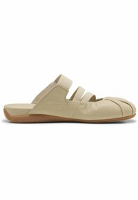 Μπεζ παπούτσι τύπου slip-on με στρογγυλεμένο, διαιρεμένο σχεδιασμό μύτης, ελαστικούς ιμάντες πάνω από το κέντρο του ποδιού και καφέ λαστιχένια σόλα.