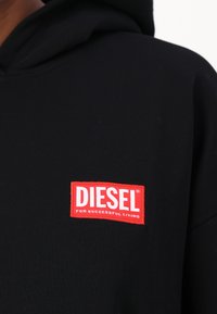 Moleton preto de algodão com um retângulo vermelho com a inscrição "DIESEL" e "FOR SUCCESSFUL LIVING" em branco. Design simples, sem padrões.