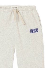 Heledatavidest dressipüksid, valmistatud pehmest kangast, millel on elastne vöökoht, pael ja sinine "AMERICAN VINTAGE" logo küljes.