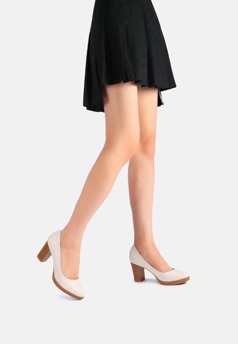 Décolleté beige con punta rotonda, tacco a blocco marrone texturizzato, superficie liscia e design minimalista.