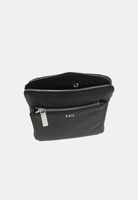 Borsa a tracolla in pelle nera con una texture liscia, chiusura con zip, tasca esterna e dettagli in metallo argentato. Presenta il logo sulla parte anteriore.