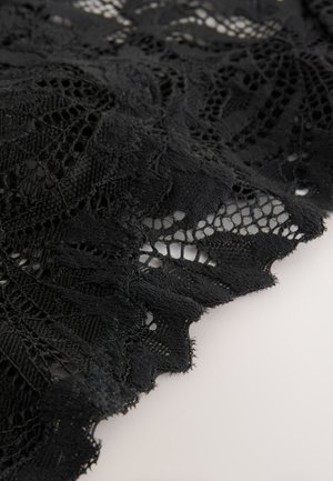 Čierna čipková látka s kvetinovými vzormi, precízne tkaná s rôznymi textúrami. Okraje sú vlnité, čo zvýrazňuje dizajnové detaily.