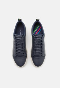 Marlové modré kožené tenisky s bílými podrážkami, černými tkaničkami a patními špunty a stélkami s duhovým pruhem, z pohledu shora na bílém pozadí.