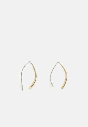 Paire de boucles d'oreilles fines, courbées, en fil métallique doré et argenté avec des extrémités en forme de boule, sur fond blanc uni.