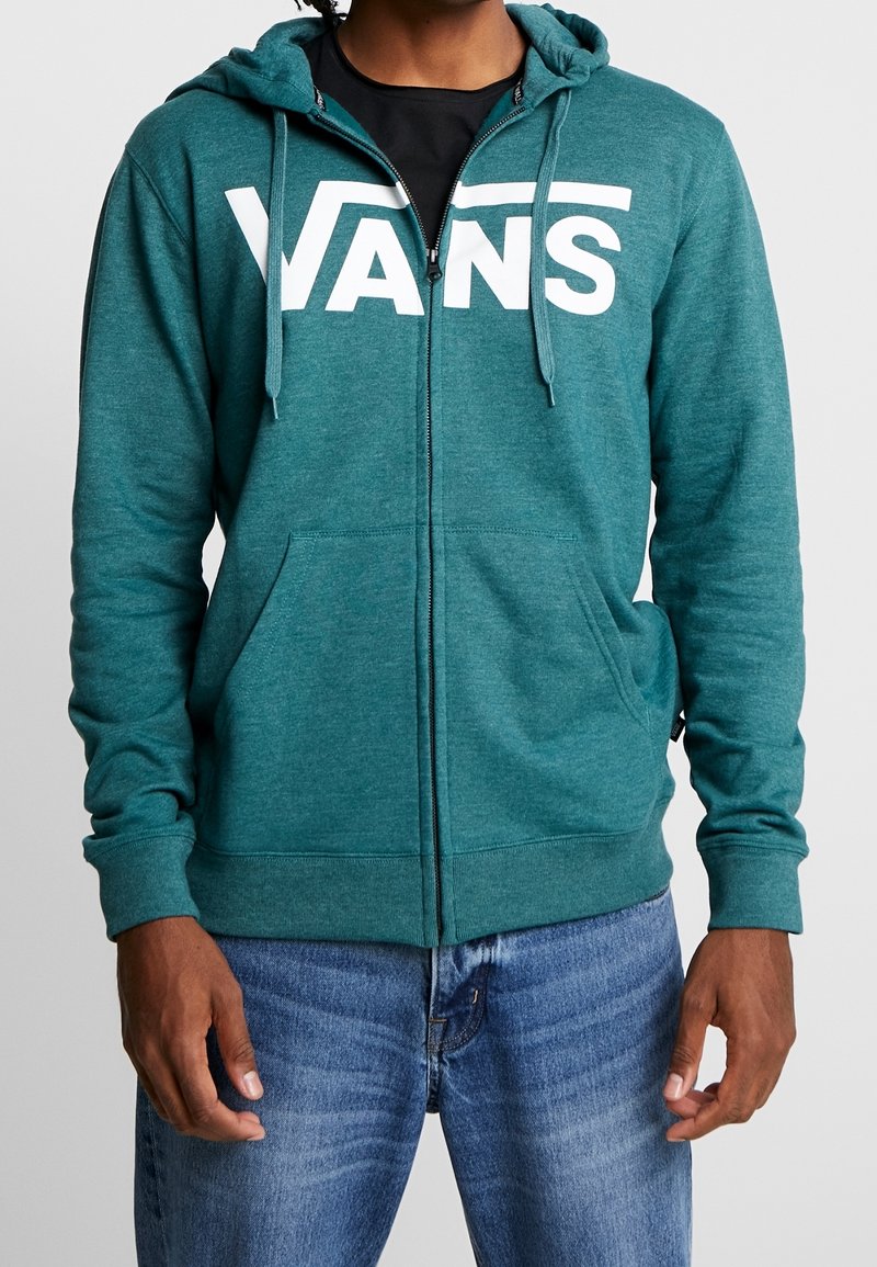 Felpa con zip di colore verde acqua con logo "VANS" bianco sul petto. Presenta un cappuccio regolabile con cordino e tasche frontali, realizzata in tessuto strutturato.