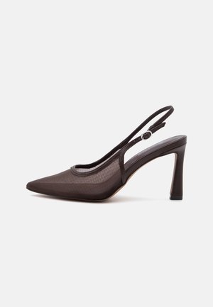 Chaussure slingback noire à talon haut avec bout pointu et bride à boucle réglable sur fond blanc.