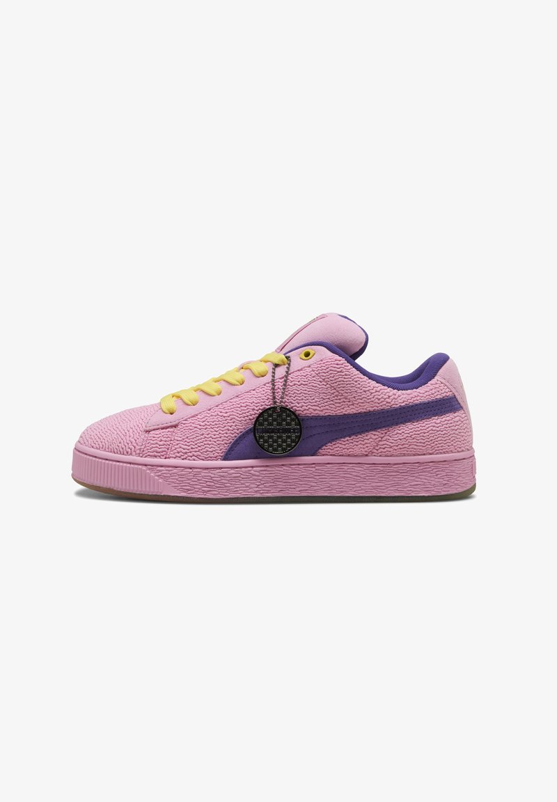 Baskets texturées roses avec des accents violets, des lacets jaunes et une étiquette circulaire noire. Elles présentent une semelle en caoutchouc avec un design strié.