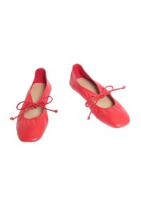 Ballerine in pelle rossa con punta arrotondata, bordo elastico arricciato e fiocchi regolabili sul davanti. Texture liscia, design minimalista.