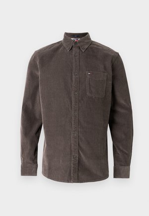 Pruun triibuline kõrge kaelusega triiksärk, millel on krae, pikad varrukad, rinnatasku ja peen vertikaalne sooniline tekstuur. Rinnataskul on logo detail.