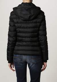 Black puffer jacket with a hood, featuring a quilted design, horizontal seams, and a shiny outer material. Worn with blue jeans.