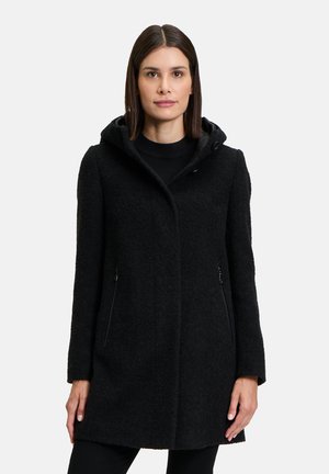 Black, textured coat with hood, long sleeves, and zippered side pockets. Features a streamlined silhouette and a soft, warm fabric.