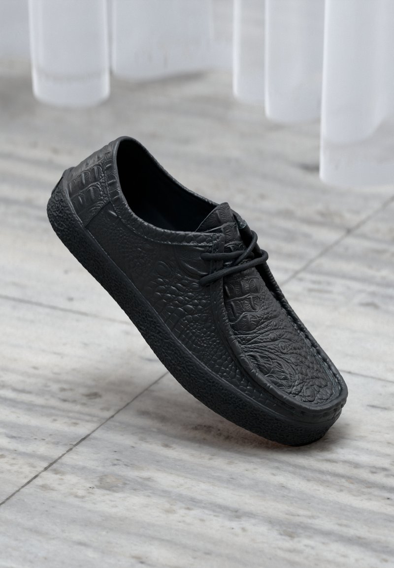 Swarte faux lærersneakers med krokodille tekstur, rund tå og snørebånddesign. Teksturert gummi såle gir grep og holdbarhet.