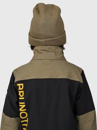 Chaqueta negra y oliva con un cuello corto, presenta grandes letras amarillas en la parte posterior. El portador lleva un gorro de punto oliva a juego.