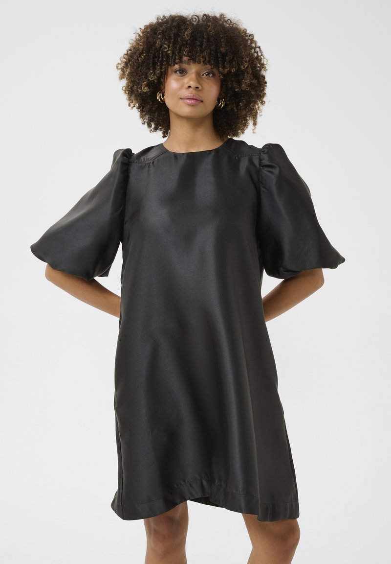 Svart satin klänning med puffade korta ärmar och rund halsringning. Slät textur och lös passform, som slutar strax ovanför knäna.