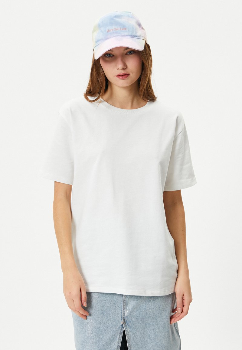 Vit bomull t-shirt med korta ärmar, rund halsringning, tillsammans med en pastellfärgad tie-dye keps med broderad text.