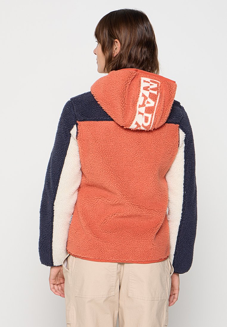 Sudadera de forro polar en naranja, azul marino y crema. Tejido grueso y texturizado con un logotipo prominente en la capucha. Diseño a bloques de colores con un corte relajado.