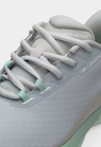 Lysegrå Skechers Slip-In-sneaker med hvite lisser og mintgrønne hull, med fremhevet polstret tunge og teksturert såle.