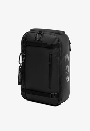 Schwarzer, wasserfester Rucksack mit rechteckiger Form, mehreren Fächern, Reißverschlüssen, verstellbaren Tragegurten und einem Logo an der Seite.