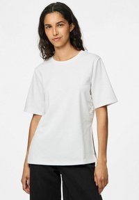 Hvid bomulds T-shirt med korte ærmer, rund halsudskæring og en afslappet pasform. Har en glat overflade og lette sidespalter ved kanten.