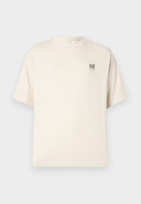 Beige T-Shirt mit kurzen Ärmeln und Rundhalsausschnitt, mit kleinem schwarzen Text "THE HAZE JAZZ LOUNGE" auf der linken Brust.