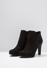 Schwarze Wildleder-Stiefeletten mit einer glatten Oberfläche, runder Spitze und einem hohen Absatz. Verfügt über einen seitlichen Reißverschluss für einfaches An- und Ausziehen.