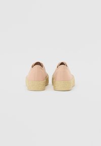 Light pink canvas shoes with a textured espadrille sole, featuring a round toe and minimal stitching details.