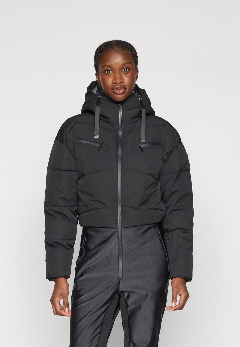 Must värviline pehme talvemantel kõrge kaelusega, kahe lukuga rinnataskuga ja reguleeritavad nöörid kapuutsil. Sile kangast tekstuur.