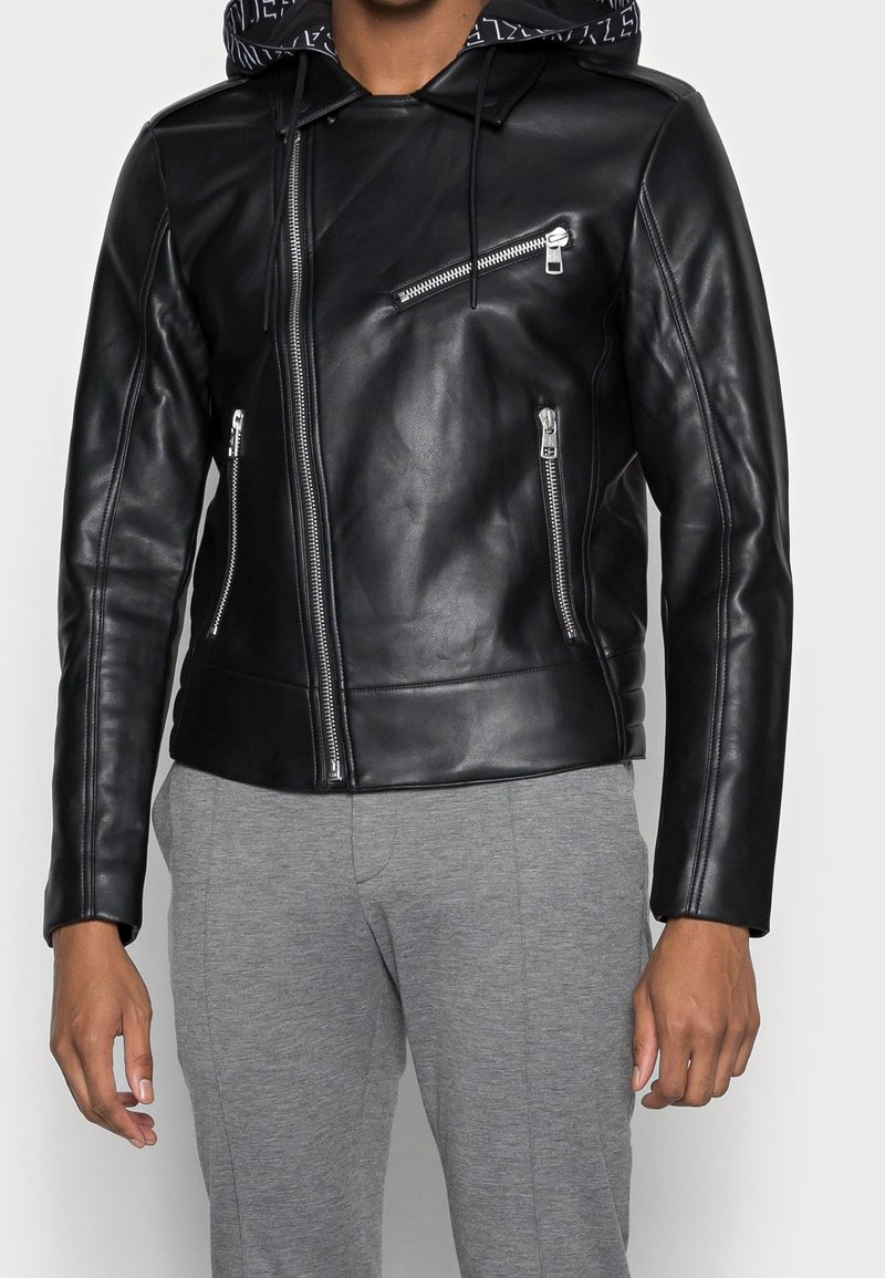 Giacca da moto nera in pelle con cappuccio, dotata di zip in argento e vestibilità slim. La giacca ha una texture liscia e un design moderno.