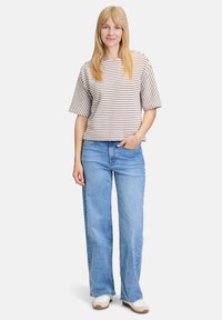 Stripet kortærmet top med afslappet pasform, parret med højtaljede lyseblå jeans. Hvide sneakers med brune accenter fuldender looket.