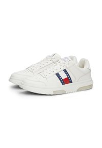 Sneakers bianchi con finitura in pelle liscia. Presentano una striscia decorativa blu, rossa e bianca e fori sulla punta per la traspirabilità.