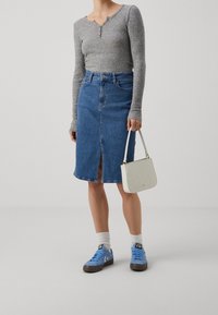 Graues, geripptes Langarmshirt, Jeans-Bleistiftrock mit Schlitz vorne, blaue Sneakers, weiße Tasche mit strukturiertem Finish.