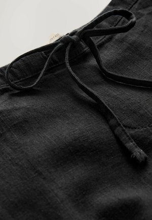 Șorturi negre din in, cu talie reglabilă prin șnur și suprafață texturată. Include un mic detaliu de buzunar cusut.