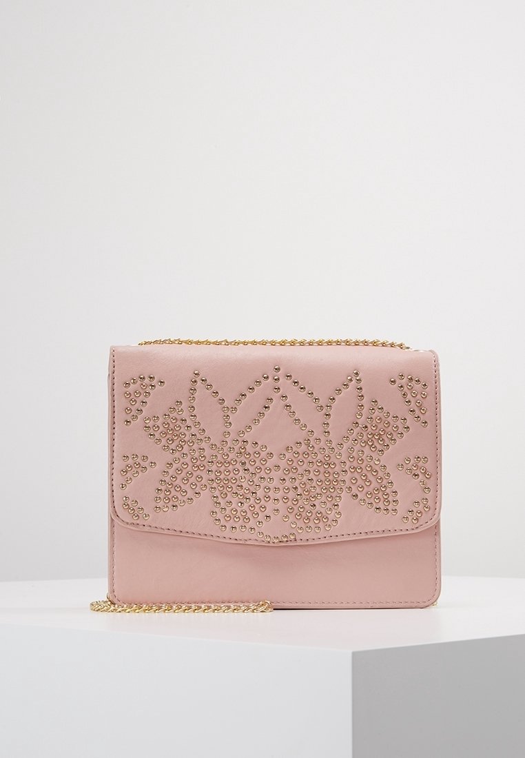 Borsa a pochette in pelle rosa con motivo floreale in borchie dorate e tracolla in oro, posizionata su un piedistallo bianco su uno sfondo neutro.