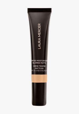 Laura Mercier fargetilpasset fuktighetskrem i en svart tube med matt finish. Har fet tekst og en beige seksjon som angir SPF 30 for solbeskyttelse.