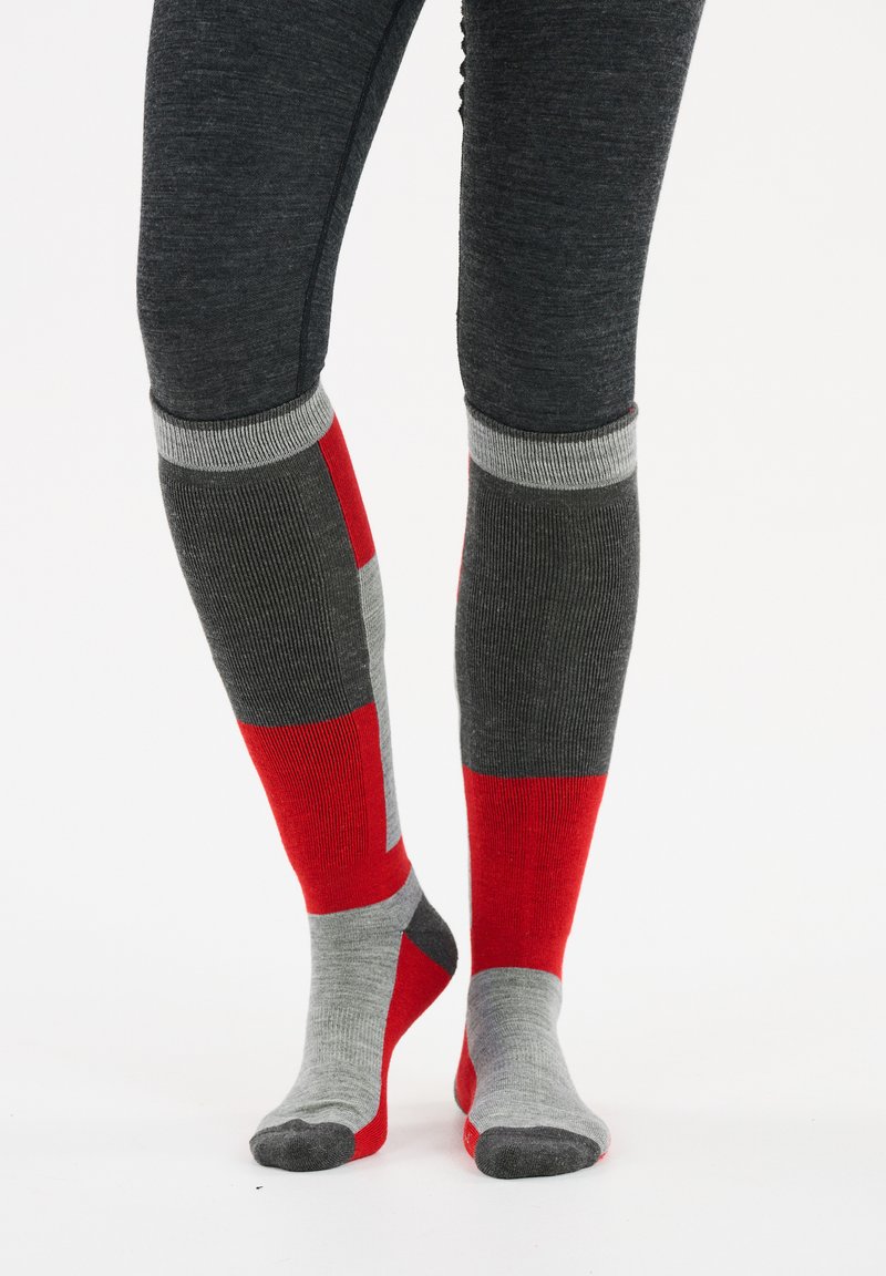 Kniesocken mit einem Patchwork-Design in Grau, Rot und Hellgrau, mit geripptem Muster und kontrastierenden Farbbereichen.