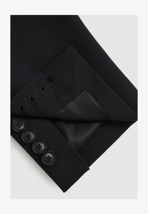 Svart skräddarsydd jackärm med ett glättat tyg, fyra svarta knappar och en sidentapet innerficka med dekorativ sömnad.