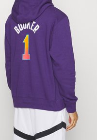 Sweat à capuche violet avec un "Booker" coloré et un "1" au dos. Tissu doux, manches longues et une poche kangourou à l'avant.